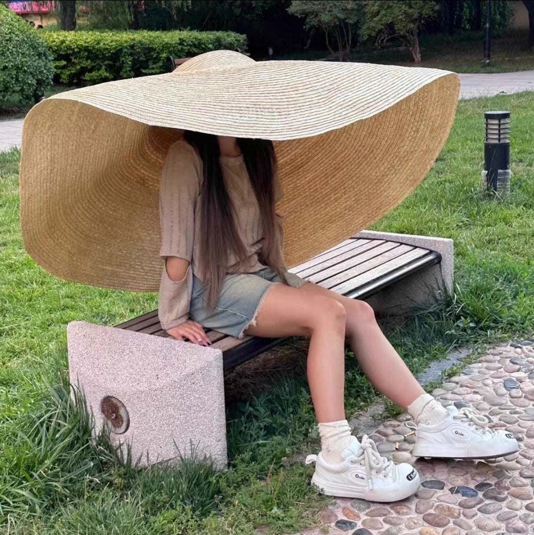 Flat lay of extra large 180cm straw beach hat in natural tan color