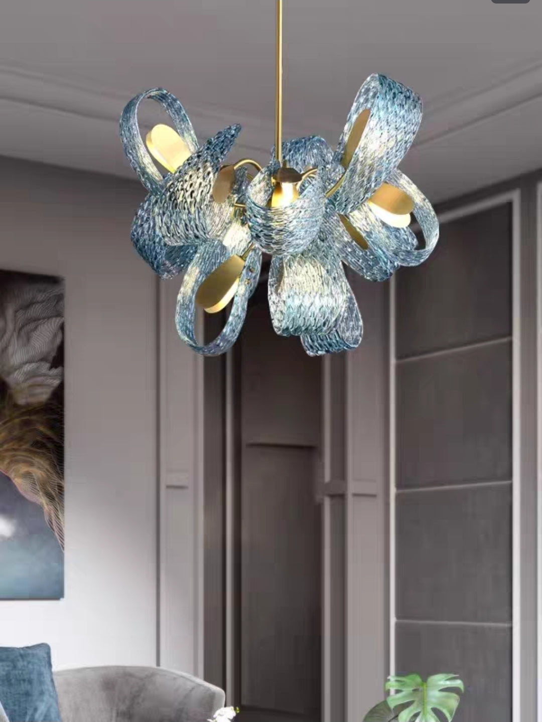 Modern chandelier with blue glass and gold accents in a room setting.