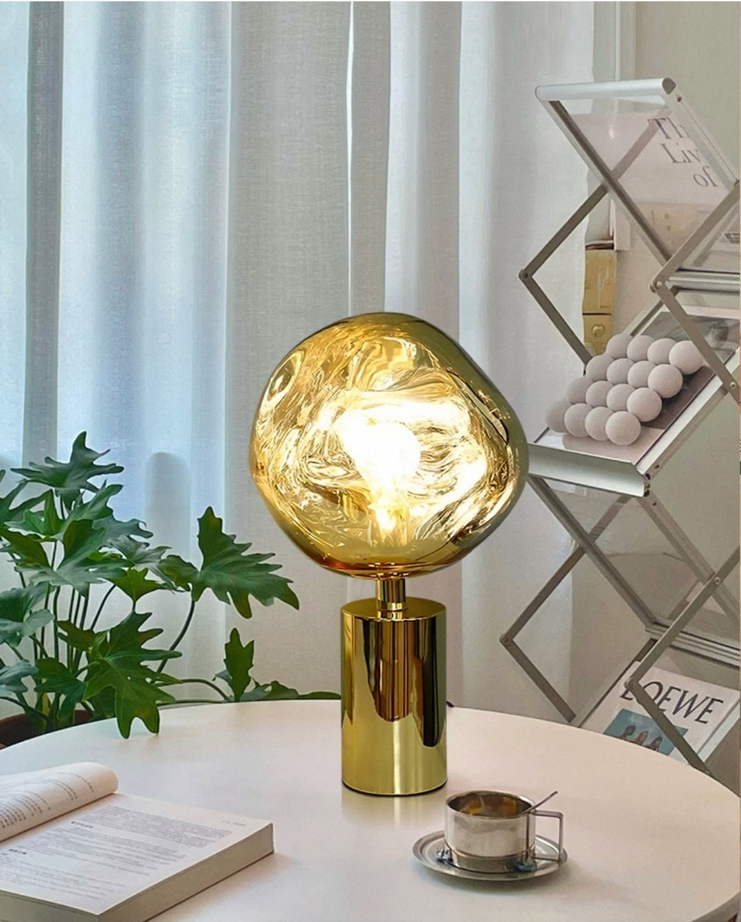 Molten glass globe table lamp with gold base styled on a minimalist desk.