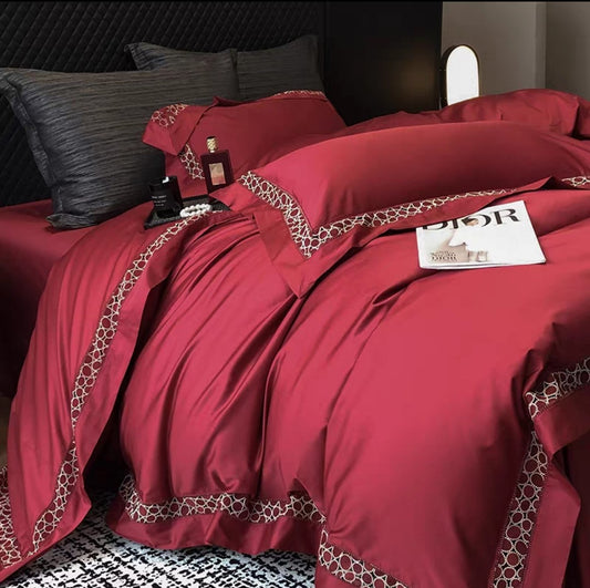 Rich red 4-piece luxury 100S long-staple cotton bedding set with geometric trim detail on duvet and pillows, styled on a black modern bed