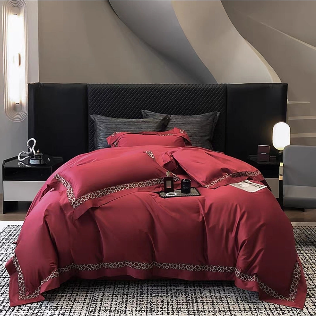 Red bedding set with embroidered detail displayed on bed frame