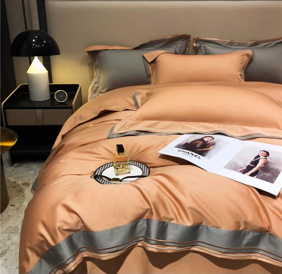 100& 100S luxury long staple bedspread with gray trim on a bed in a bedroom setting.