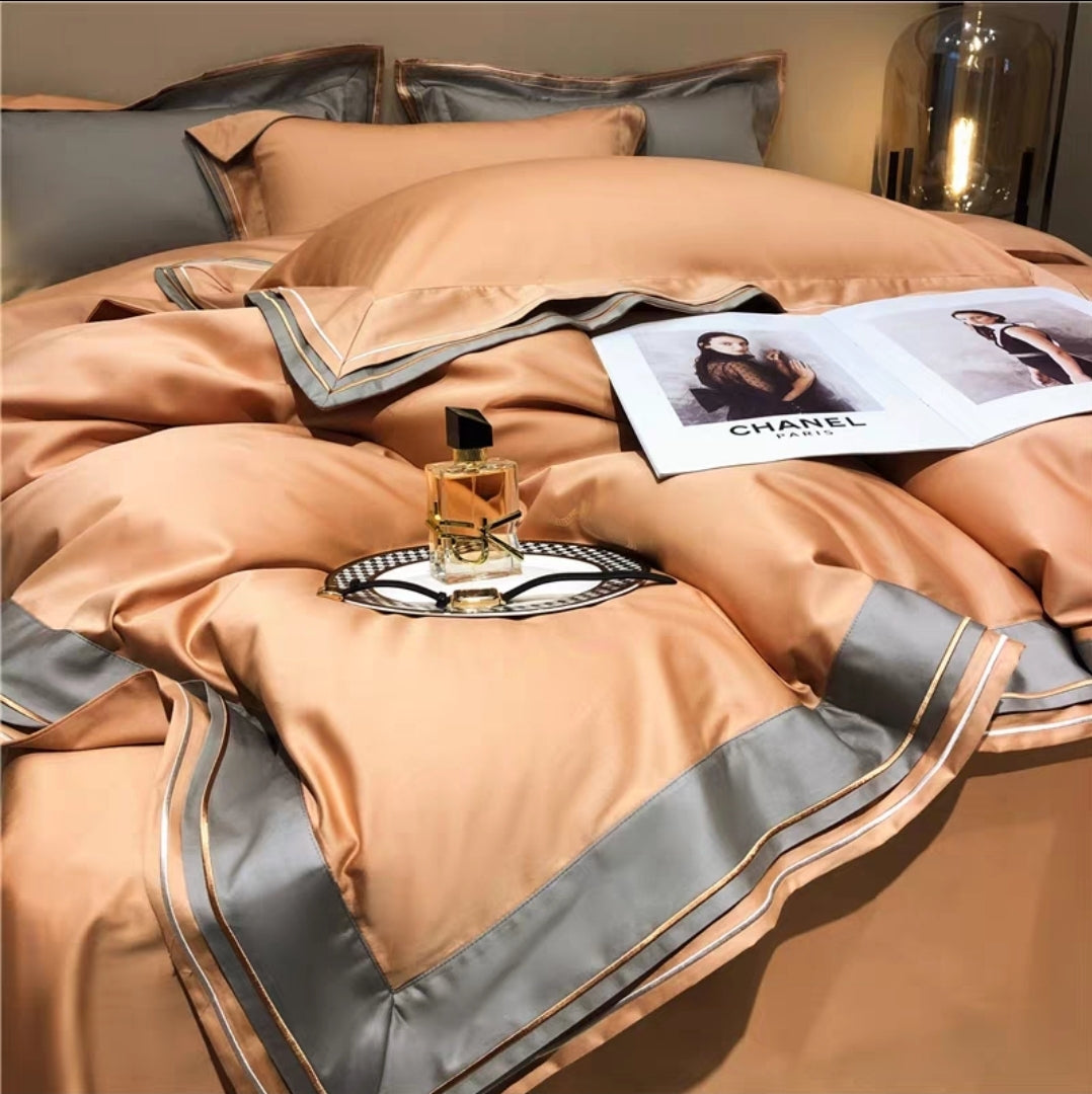 Brown and gray bedding set with a Chanel magazine and perfume bottle on a bed.
