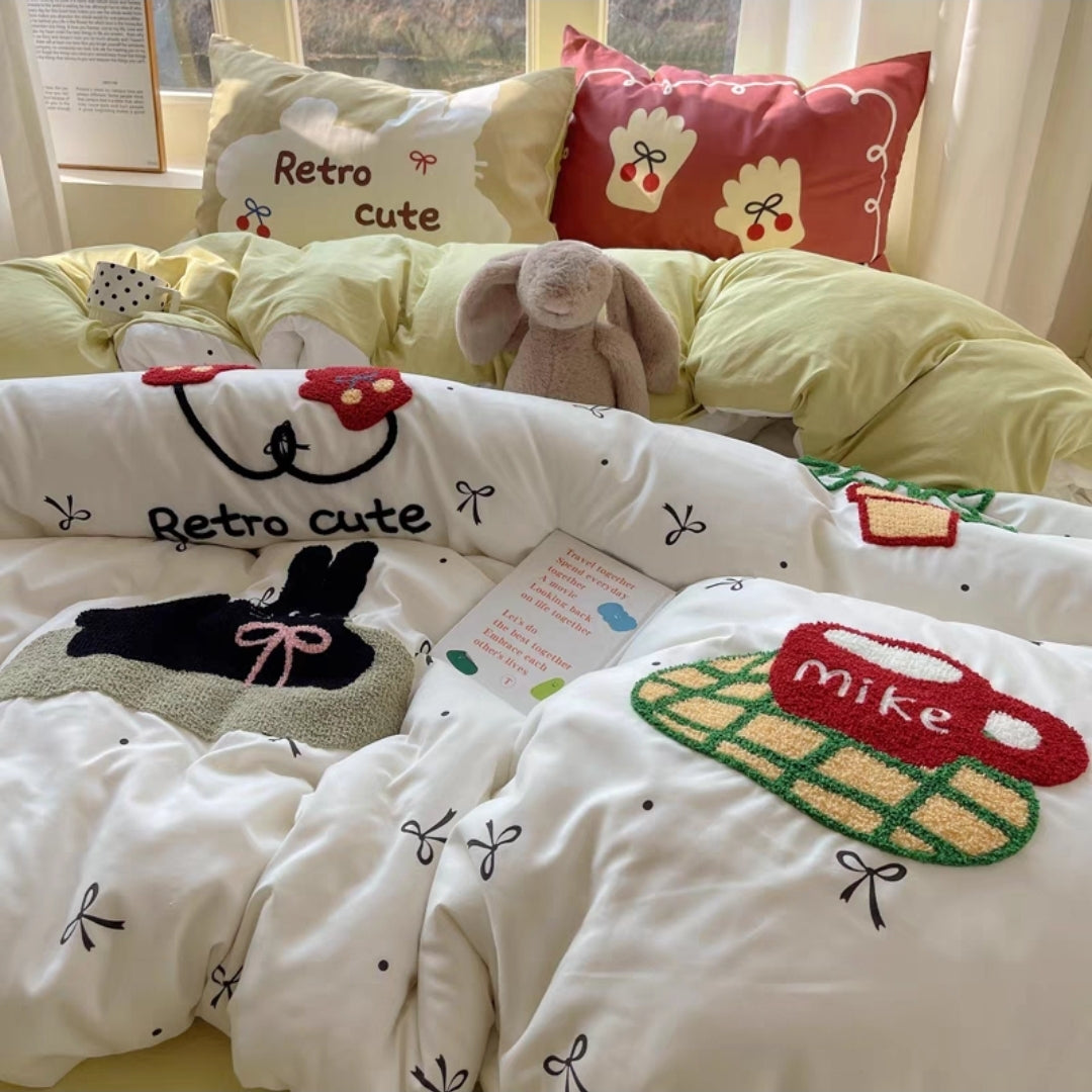 Children's bedding set with embroidered designs and text on a bed.
