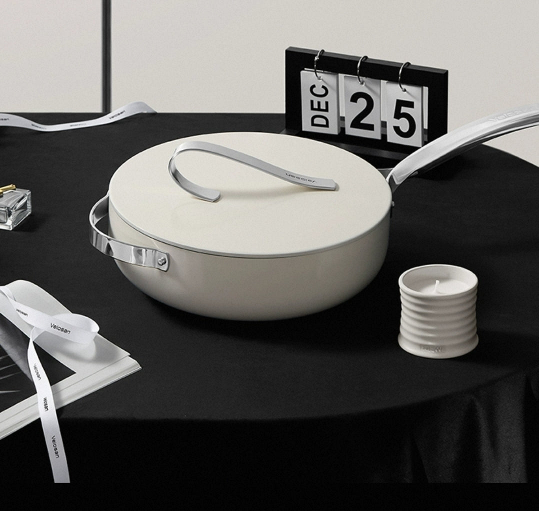 White  non-stick ceramic pot on a black table with a calendar and candle