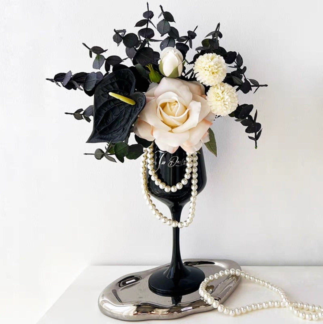 Black and white faux flower arrangement in a glossy black goblet vase with pearl strand