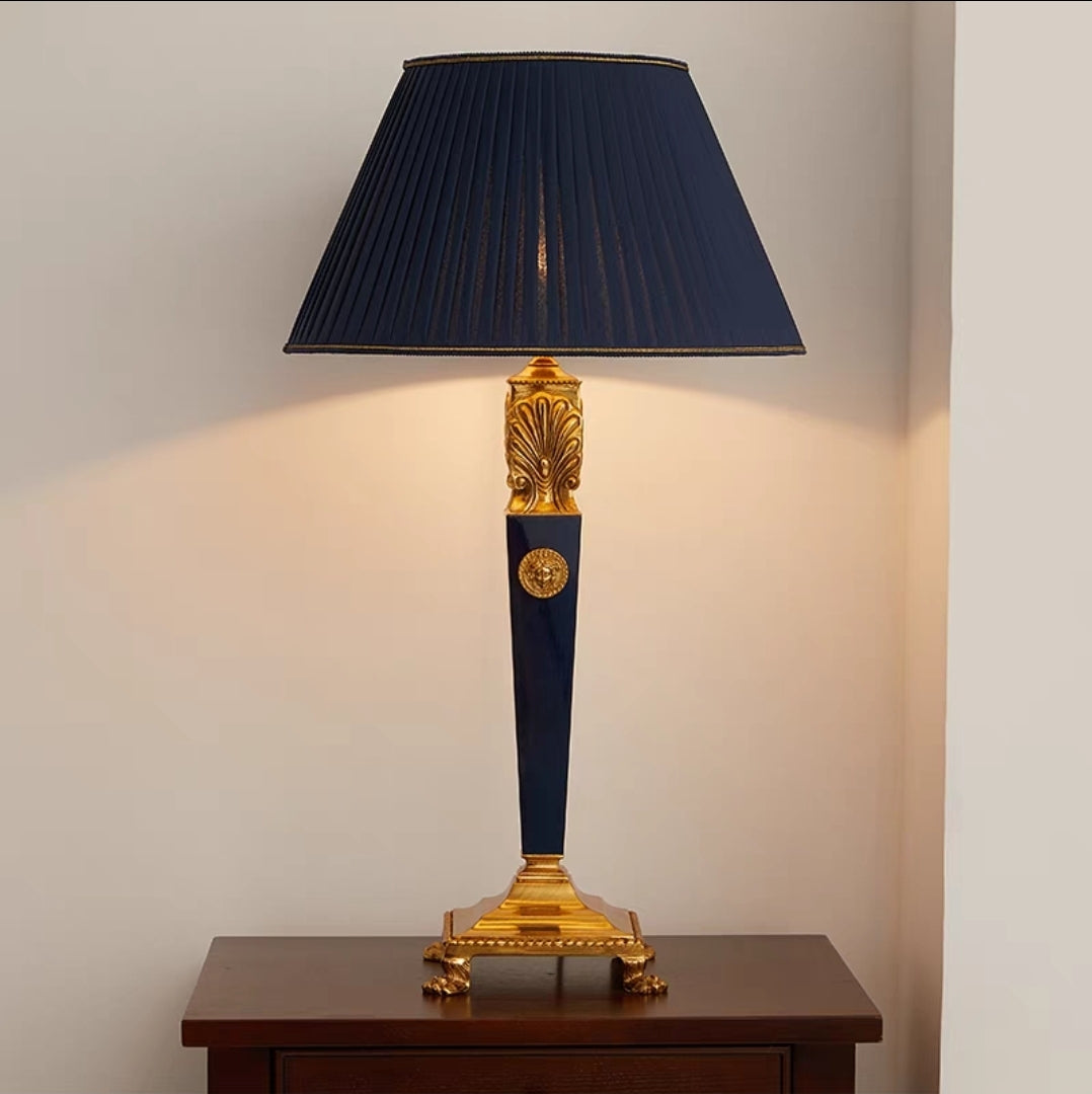 vintage brass table lamp with blue base and black shade on a wooden surface.