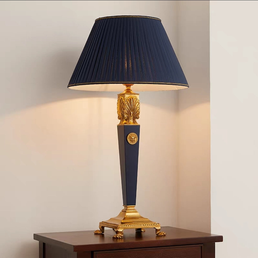 French vintage brass table lamp with a dark blue shade and gold accents on a wooden surface.