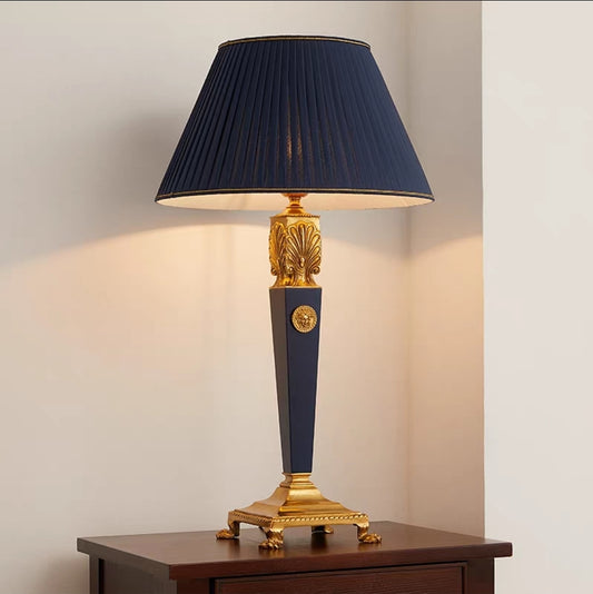 French vintage brass table lamp with a dark blue shade and gold accents on a wooden surface.