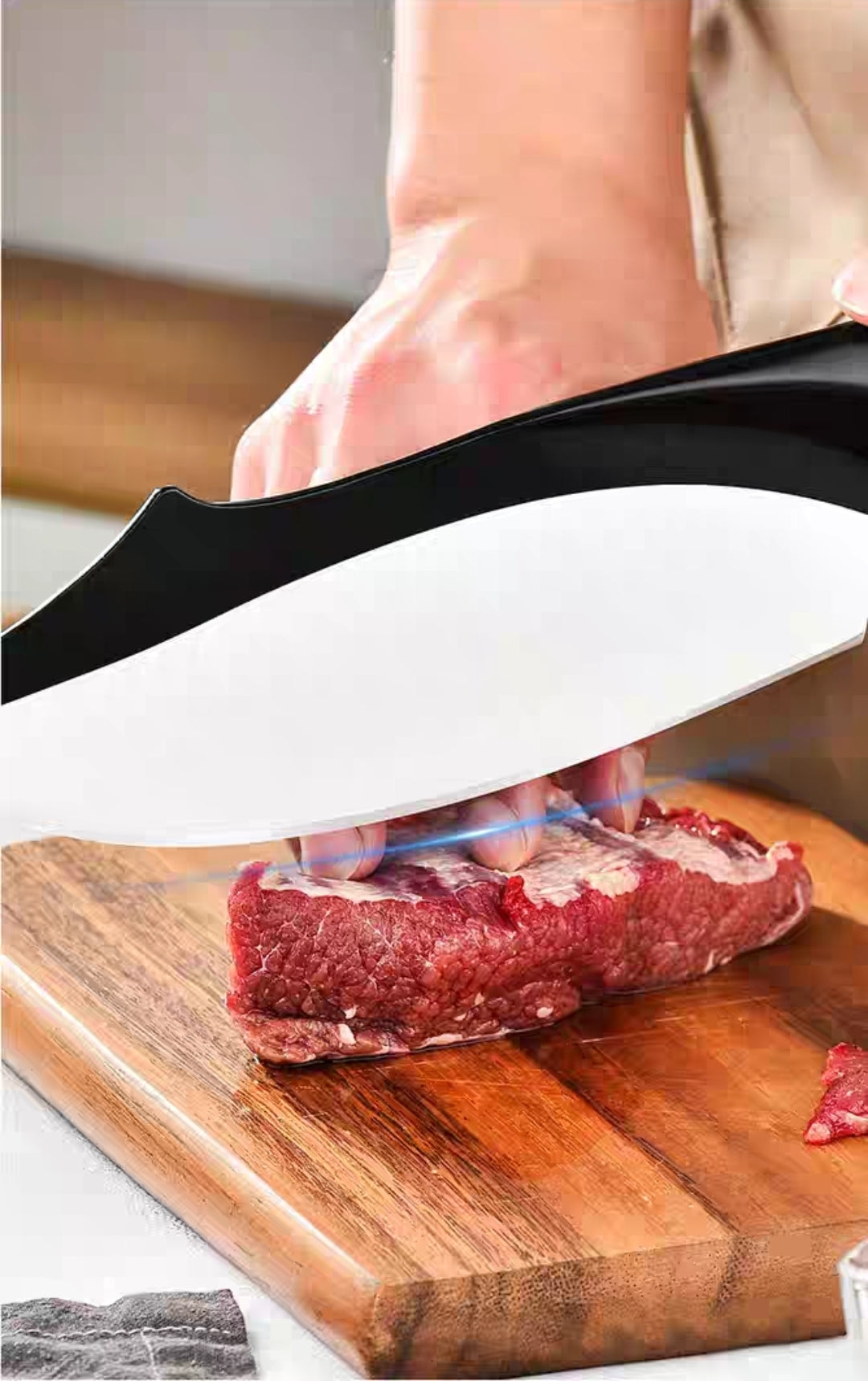 Close-up of curved-handle kitchen knife slicing meat on a wooden board
