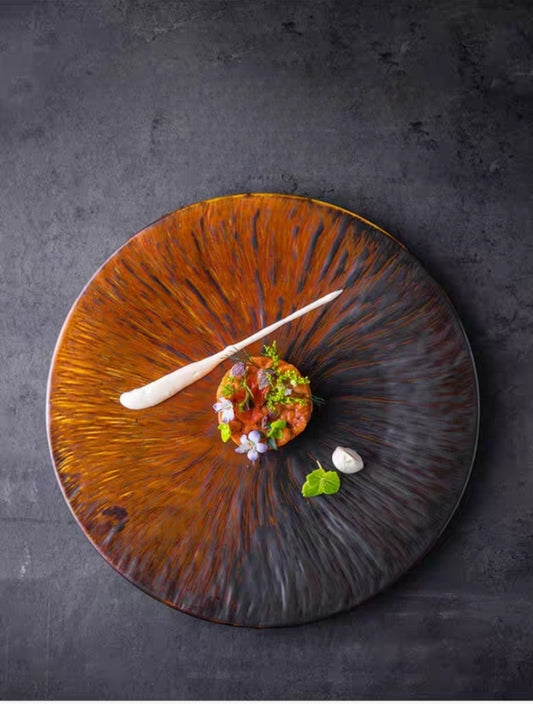 Kiln-glazed ceramic flat plate with irregular edge, matte finish, served with gourmet dish presentation
