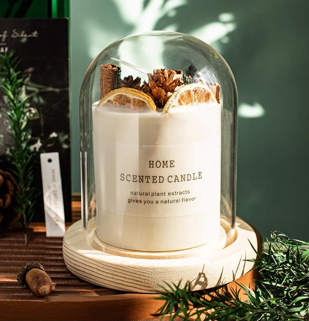 Home scented dried flower candle with natural plant extracts under a glass dome on a wooden surface.