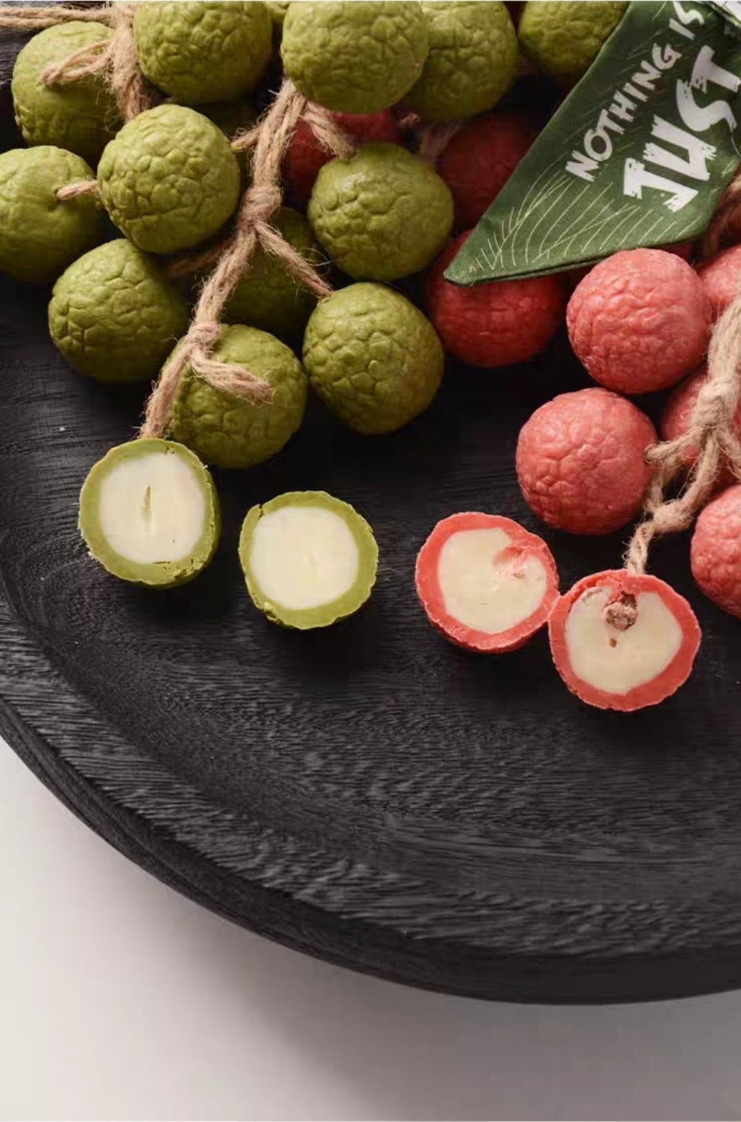 Lychees on a dark surface with a green leafy label.