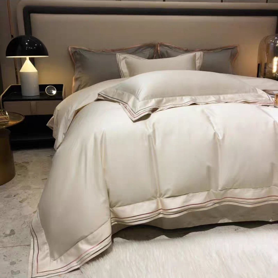 Neatly made bed with beige bedding made with 100S 100% long staple cotton in a bedroom setting.