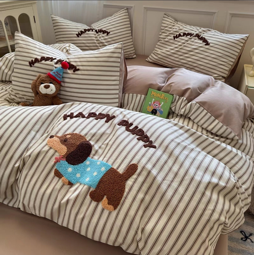 Striped bedding with a 'Happy Puppy' design on a bed in a bedroom setting.