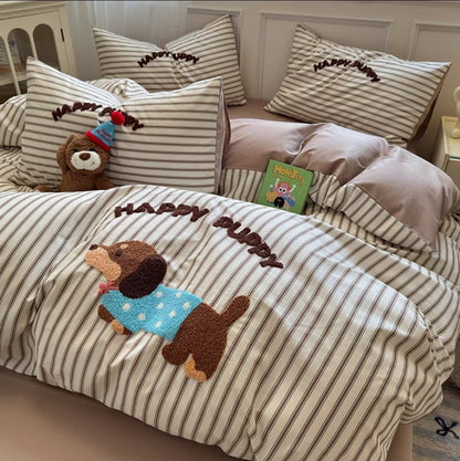 Striped bedding with a 'Happy Puppy' design on a bed in a bedroom setting.