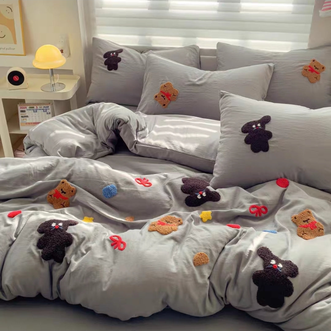 Gray cotton cartoon bedding set with embroidered animal faces on a bed in a bedroom setting.