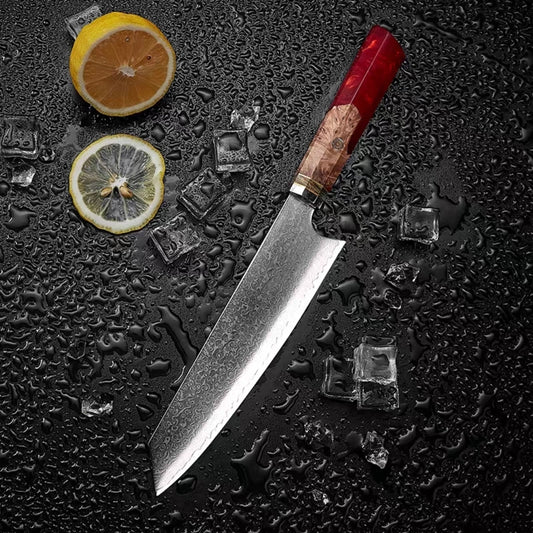 Japanese Damascus chef knife with red resin burl handle on black slate surface

