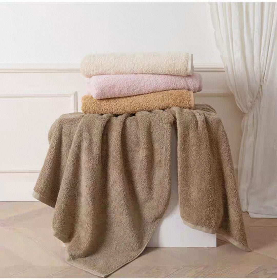 Stack of pastel bath towels in various neutral colors
