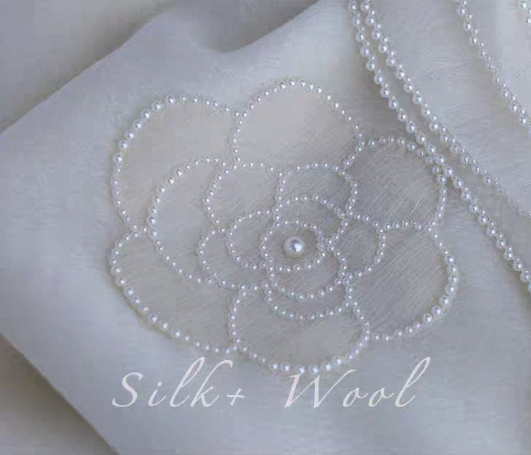 Close-up of camellia flower embroidery on luxury silk wool shawl.
