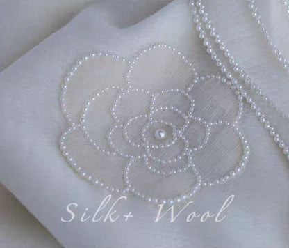 Close-up of camellia flower embroidery on luxury silk wool shawl.

