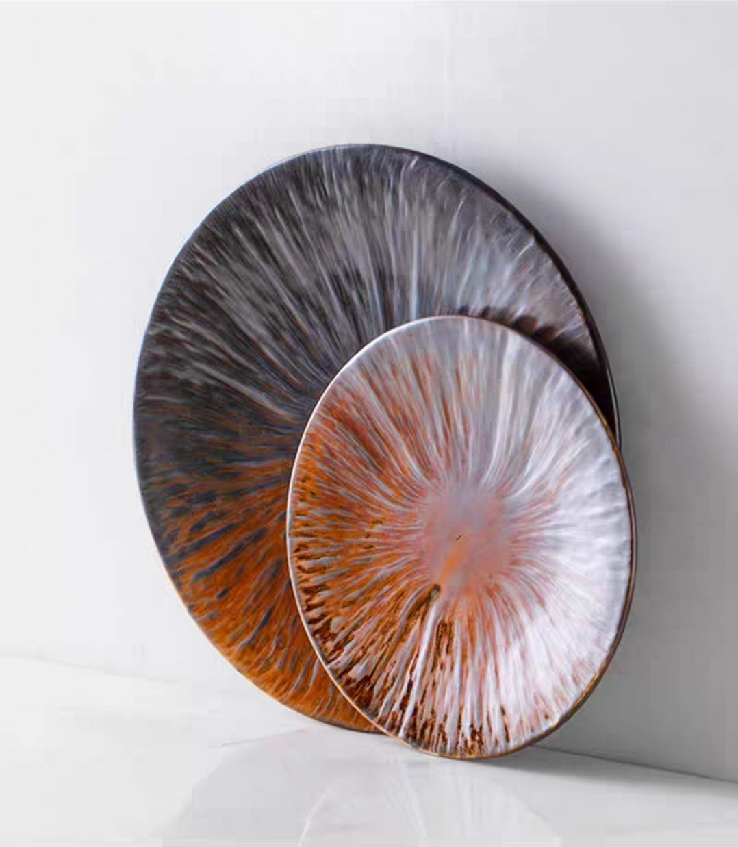 Artisan kiln-glazed ceramic flat plates in gradient brown and grey, matte texture and scalloped edge detail.